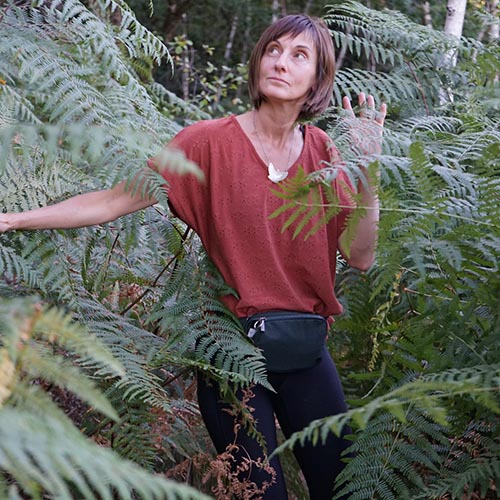 Virginie Leveaux, praticienne en sylvothérapie, s'immergeant dans une forêt de fougères pour illustrer la connexion profonde avec la nature.